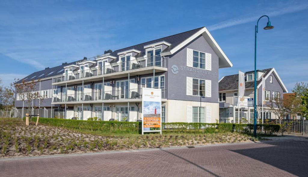 a large building with a sign in front of it at Strandplevier Suites in De Koog