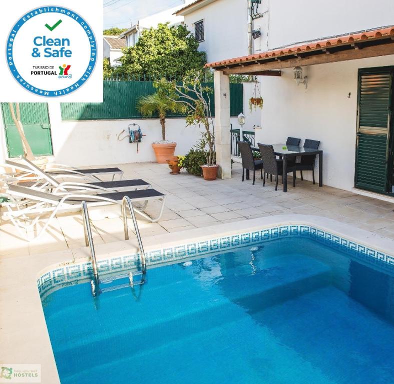 a house with a swimming pool and a table and chairs at Help Yourself Hostels - Carcavelos Coast in Carcavelos