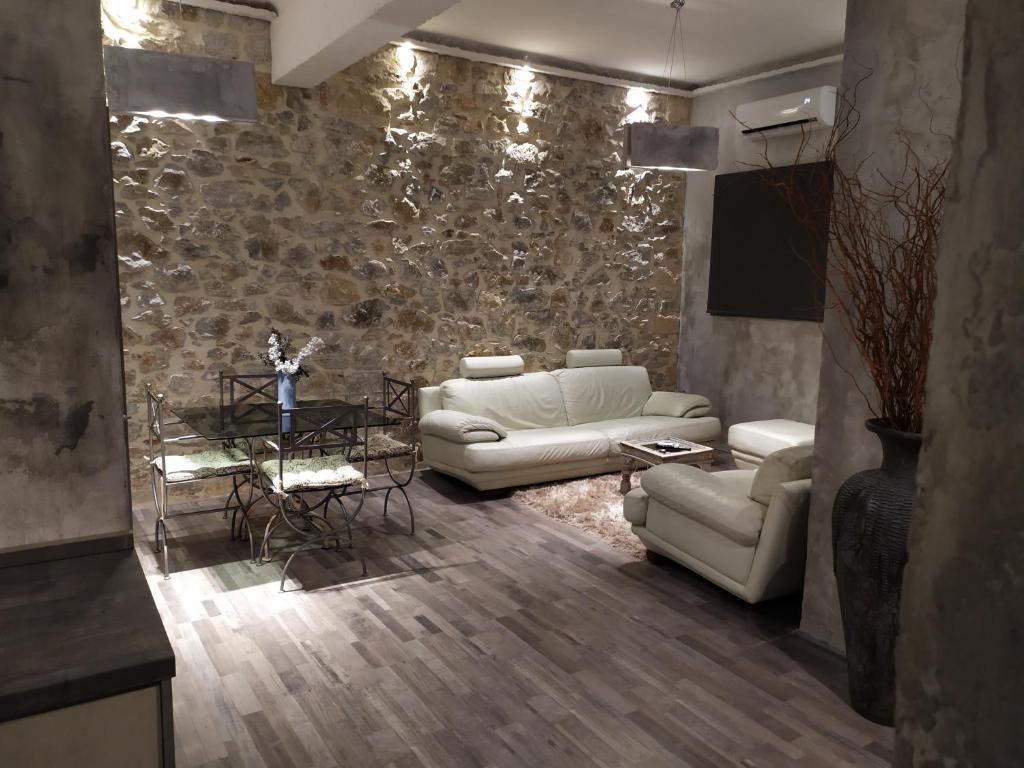 a living room with white furniture and a stone wall at Unique Luxury House in Athens