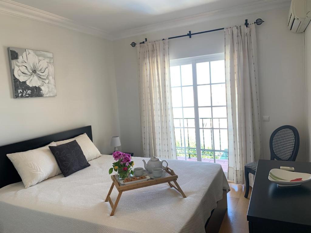 Un dormitorio con una cama y una mesa con flores. en Casa das Roseiras, en Ferragudo