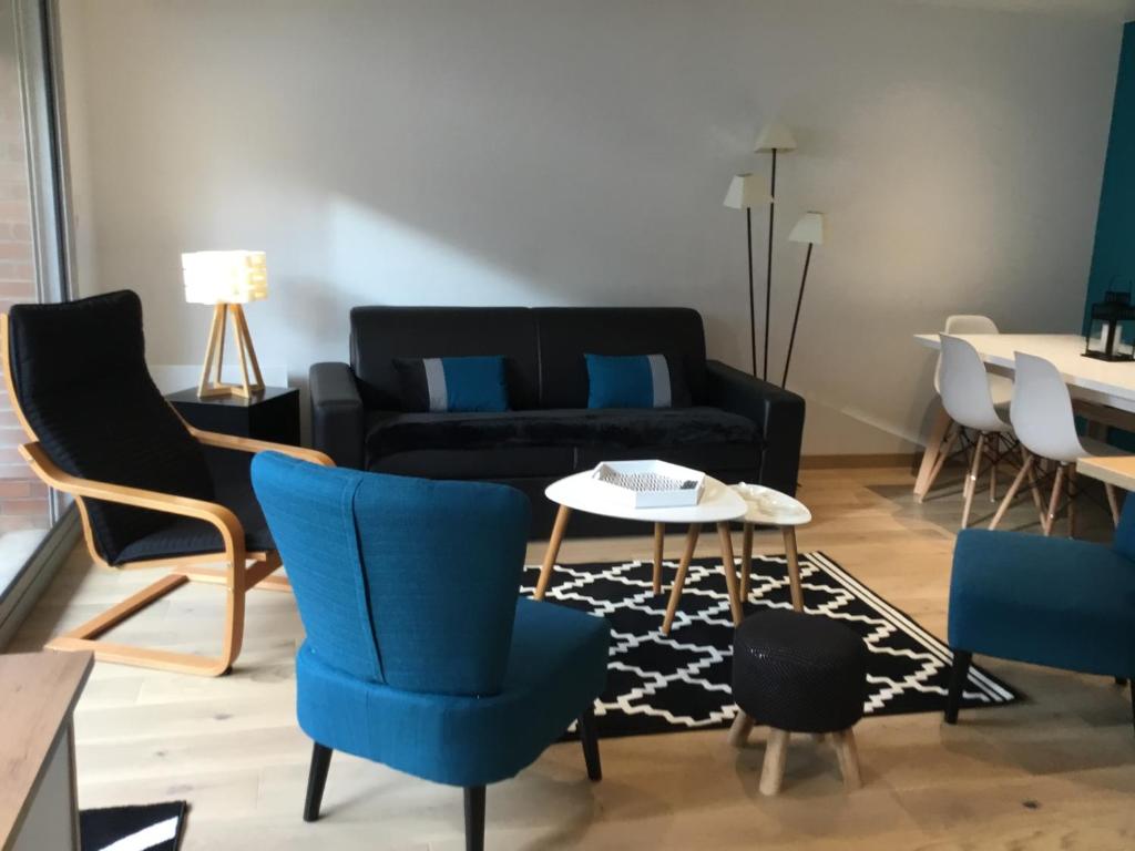 un salon avec un canapé noir et des chaises bleues dans l'établissement Splendide appartement proche de tous commodités, à Le Touquet-Paris-Plage