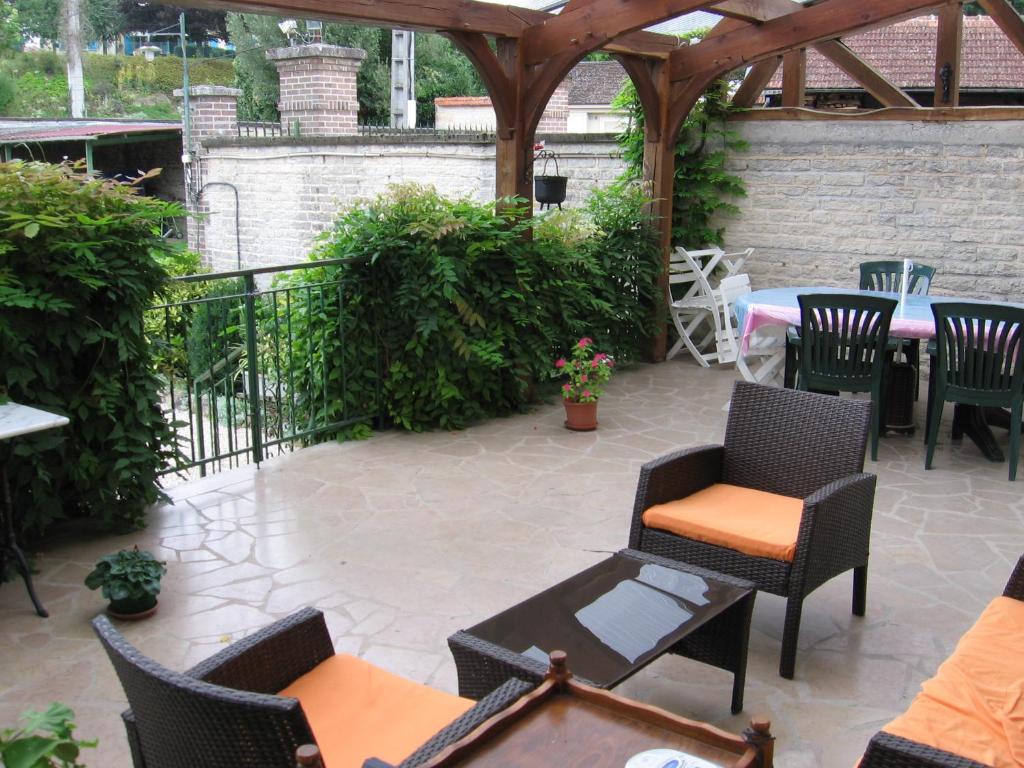 a patio with chairs and tables and a wooden pergola at Moulin de Chappes in Chappes