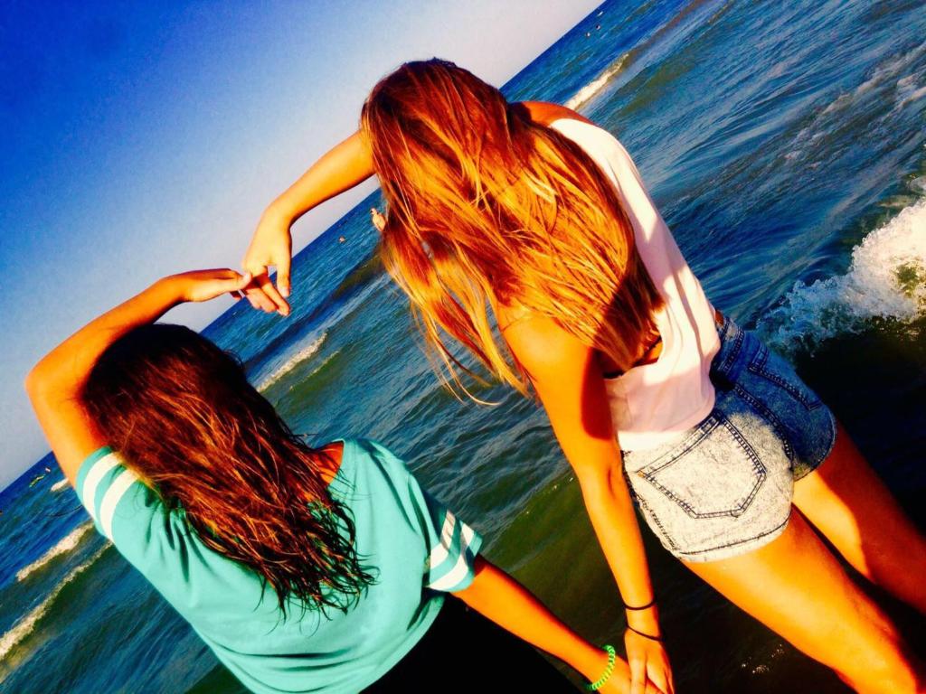 twee vrouwen staan op het strand bij het water bij Hotel Dall'Ara in Villa Marina