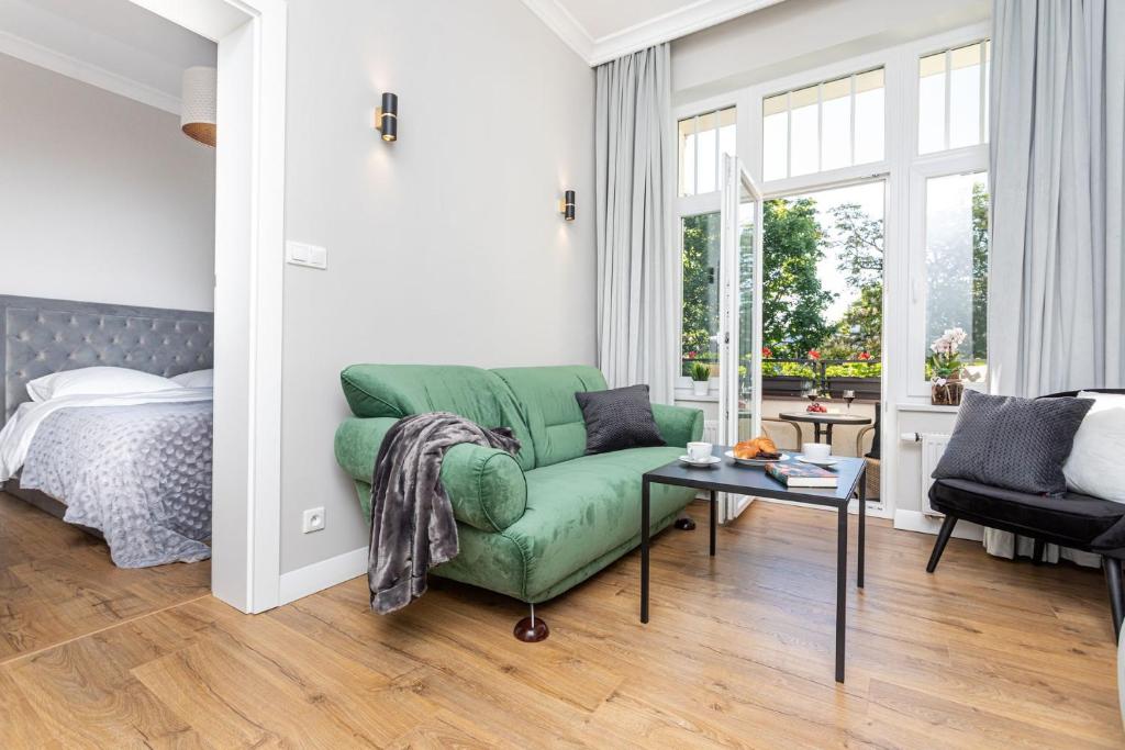 uma sala de estar com um sofá verde e uma cama em Apartamenty Vincent Sopot em Sopot