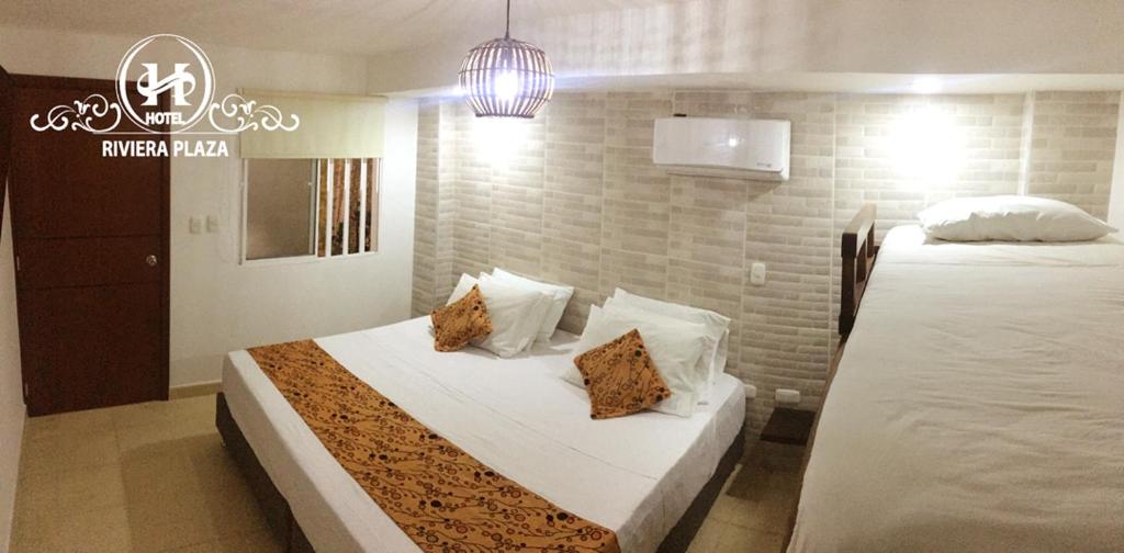 1 dormitorio con 2 camas y luz colgante en Hotel Riviera Plaza, en Bucaramanga