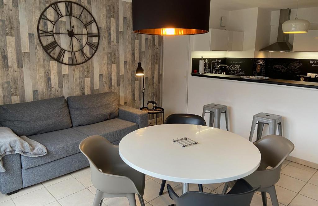 een woonkamer met een bank en een tafel met stoelen bij Lénoka in La Teste-de-Buch