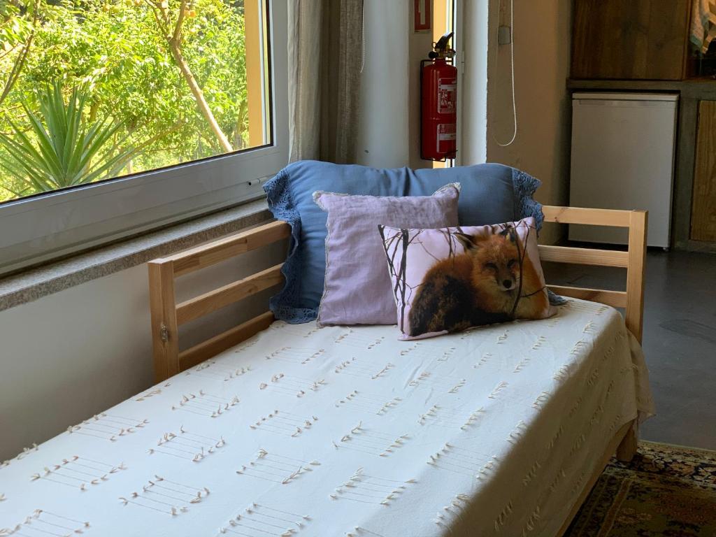 a small bed with a pillow and a window at Loft - Casinha à Porta in Arouca
