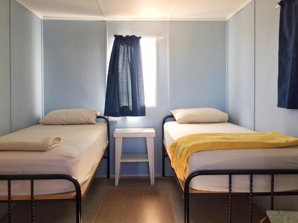 twee bedden in een kleine kamer met een raam bij Holowiliena Station & The Outback Blacksmith in Flinders Ranges