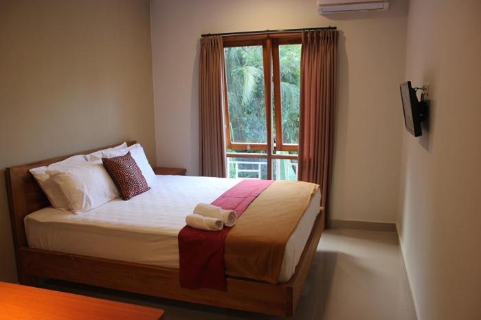 a bedroom with a bed with two towels on it at The Sarining Hotel in Tabanan