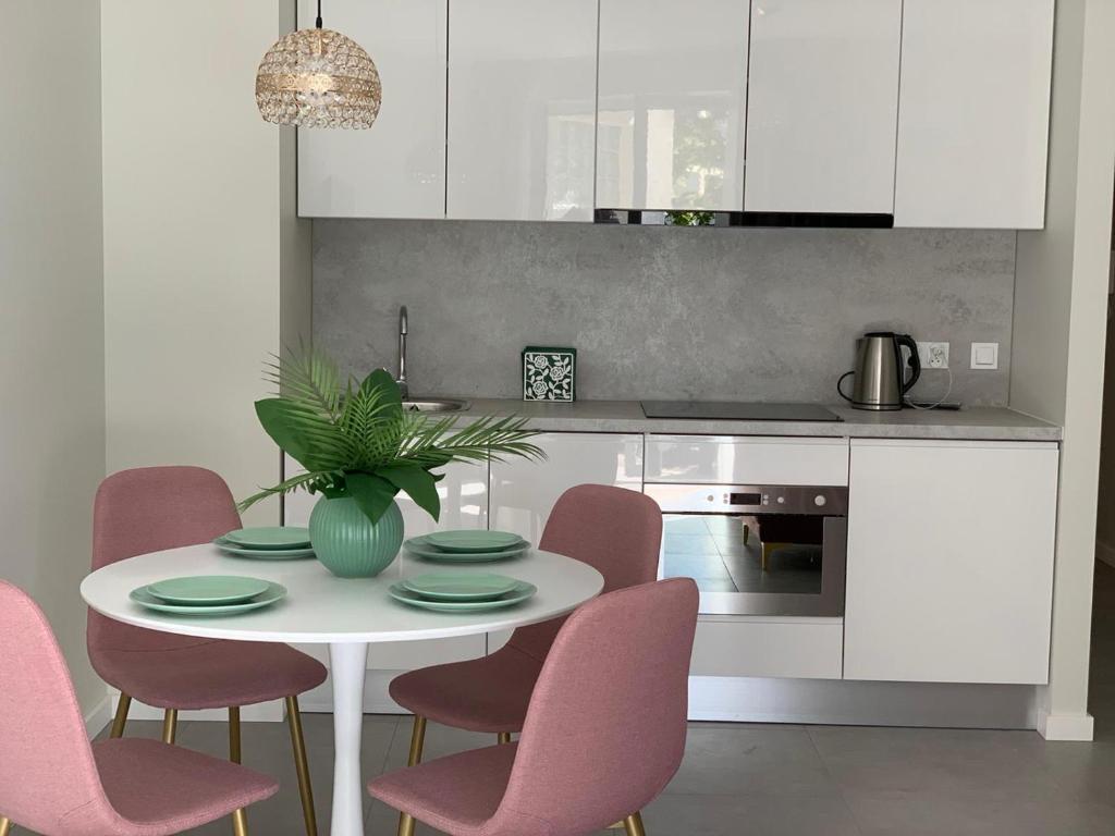 een keuken met een witte tafel en roze stoelen bij Apartament Jantarowe Zacisze Rose in Jantar