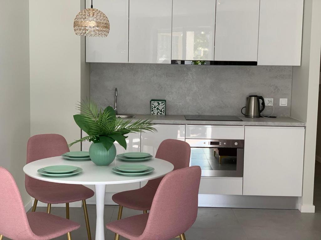 a kitchen with a white table and pink chairs at Apartament Jantarowe Zacisze Rose in Jantar