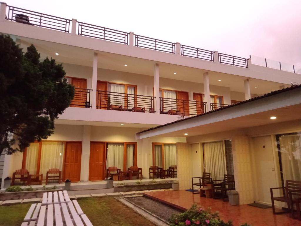 a building with a balcony and tables and chairs at Hotel Pondok Asri Tawangmangu in Tawangmangu