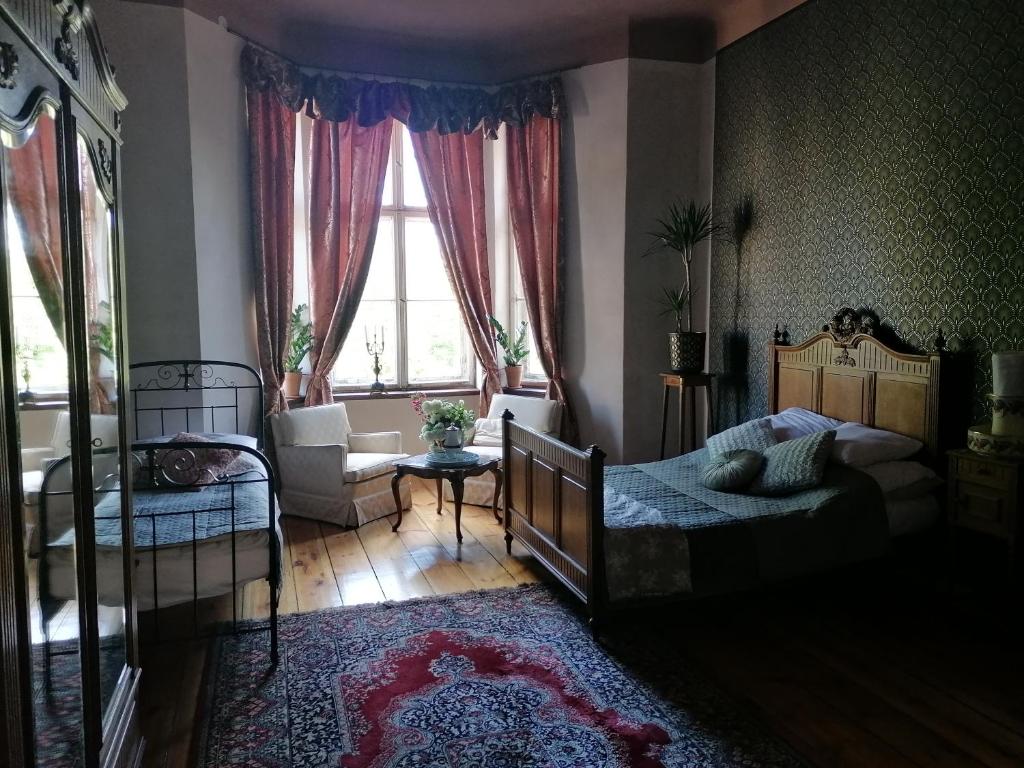 a bedroom with two beds and a chair and a window at Pałac Paprotno in Karnitz