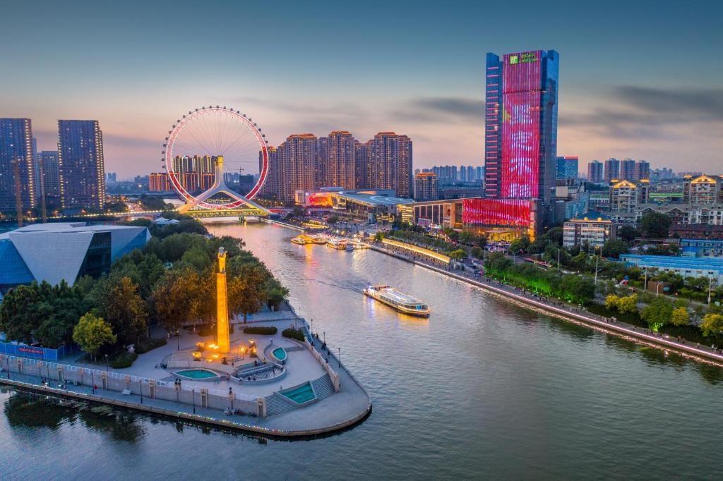 eine Stadt mit einem Fluss und eine Stadt mit hohen Gebäuden in der Unterkunft Holiday Inn Tianjin Riverside, an IHG Hotel in Tianjin