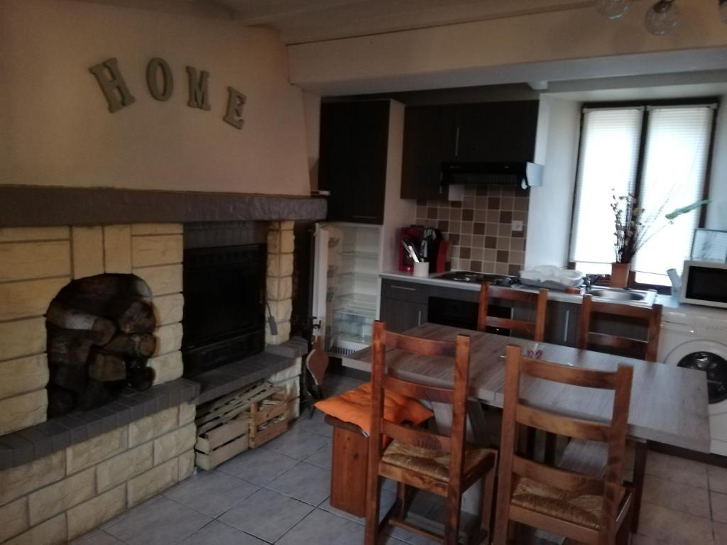 een keuken met een open haard en een tafel en stoelen bij LE GITE DE LA MAISON ROUGE in Anctoville