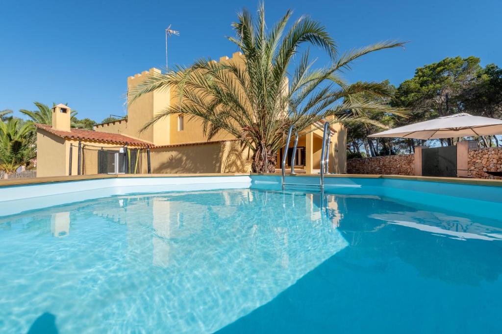 una piscina frente a una casa con palmeras en Villa Del Mar Mondrago, en Palma de Mallorca