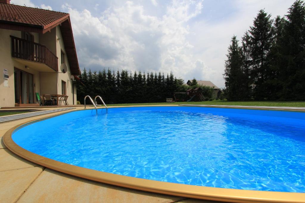 a large blue swimming pool next to a house at Villa Żywiec in Żywiec