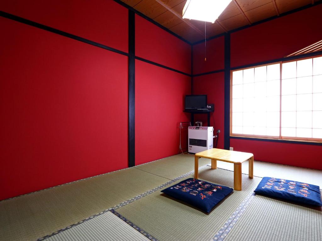 een kamer met rode muren en een tafel en een raam bij Warabiso in Yuzawa