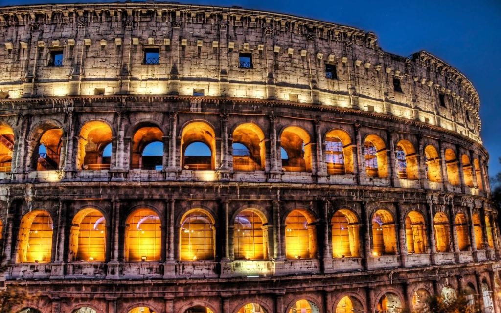 a view of the colosseum building at night at Domus Re Di Roma in Rome