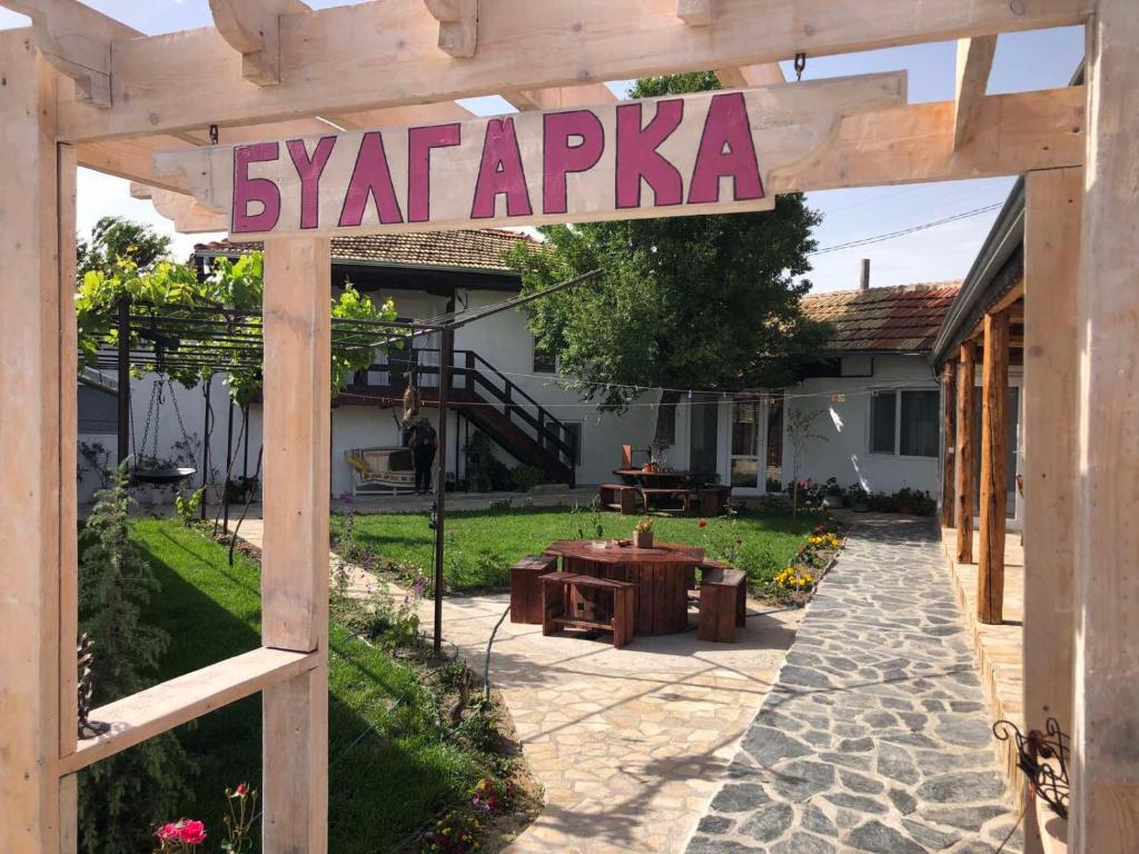 einen hölzernen Torbogen mit einem Schild im Hof in der Unterkunft Guest house BULGARKA in Dibich