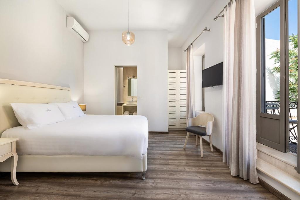 a bedroom with a white bed and a balcony at Shalom Luxury Rooms Daliani in Chania Town
