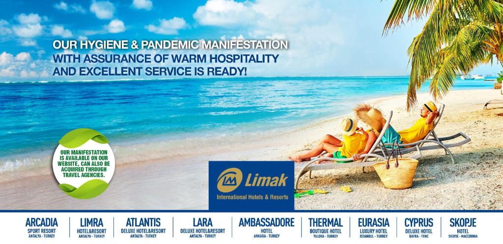 two people sitting on a beach with the ocean at Limak Arcadia Sport Resort Belek in Belek