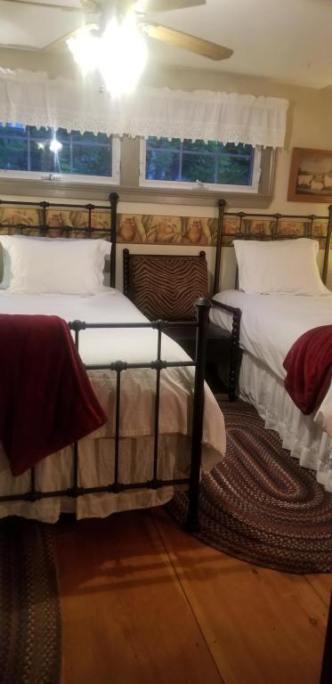 two twin beds in a room with two windows at Widow Avery House in Hallowell