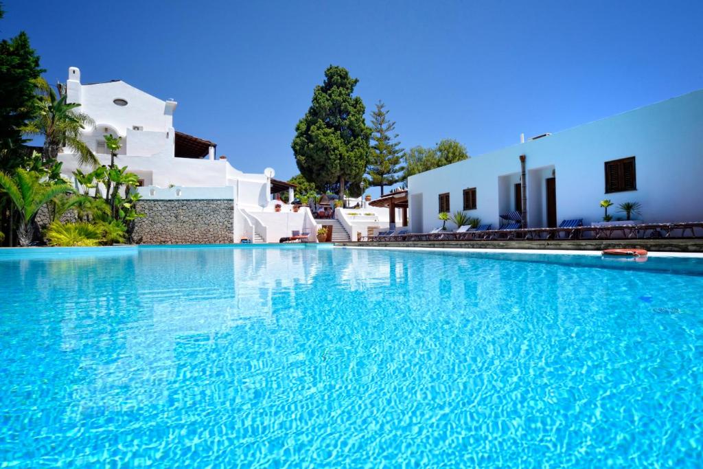 a large swimming pool with blue water in front of white buildings at Gattopardo Park Hotel in Lipari