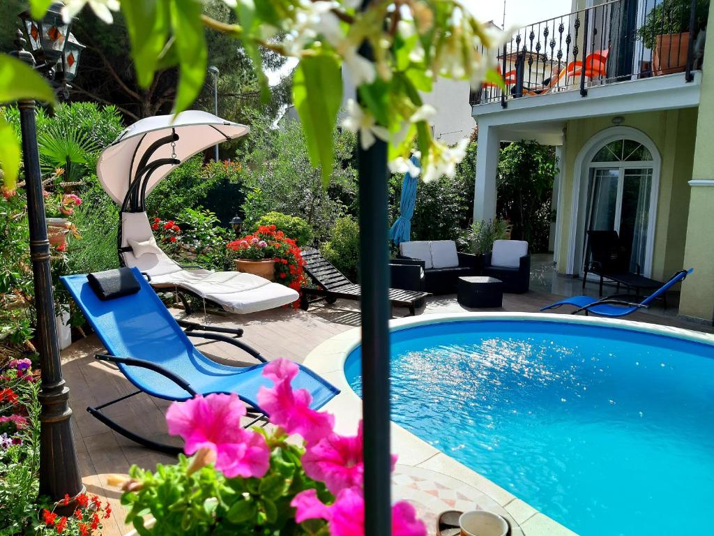 a pool with chairs and an umbrella and some flowers at Apartments Dora in Medulin