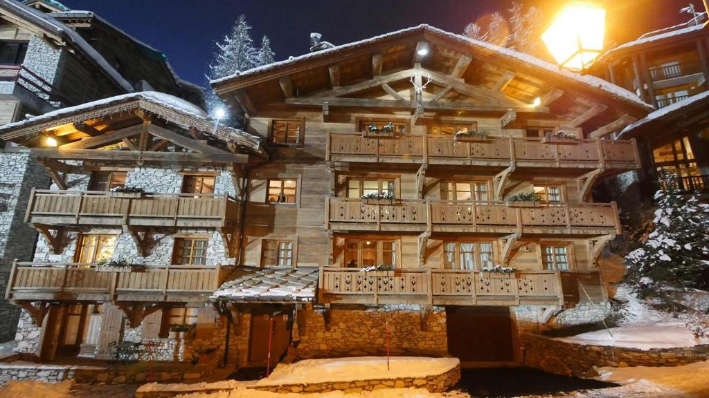 een groot houten gebouw met een balkon in de sneeuw bij Chalet Les Alpes in Val dʼIsère