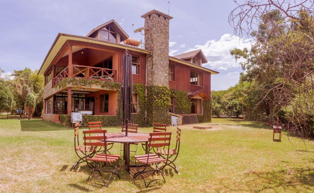 uma mesa e cadeiras em frente a uma casa em Ol-Kine Cottage at The Great Rift Valley Lodge & Golf Resort Naivasha em Naivasha