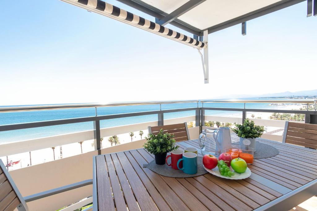 uma mesa com frutas e bebidas numa varanda com praia em Apartamento Rodas Arysal em Salou