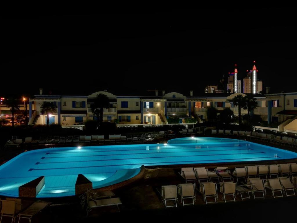 una grande piscina di notte con edifici sullo sfondo di Residence Antenore Attico Giulia a Lido di Jesolo