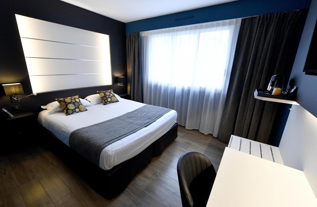 pokój hotelowy z łóżkiem i oknem w obiekcie Hôtel Des Quatrans w Caen