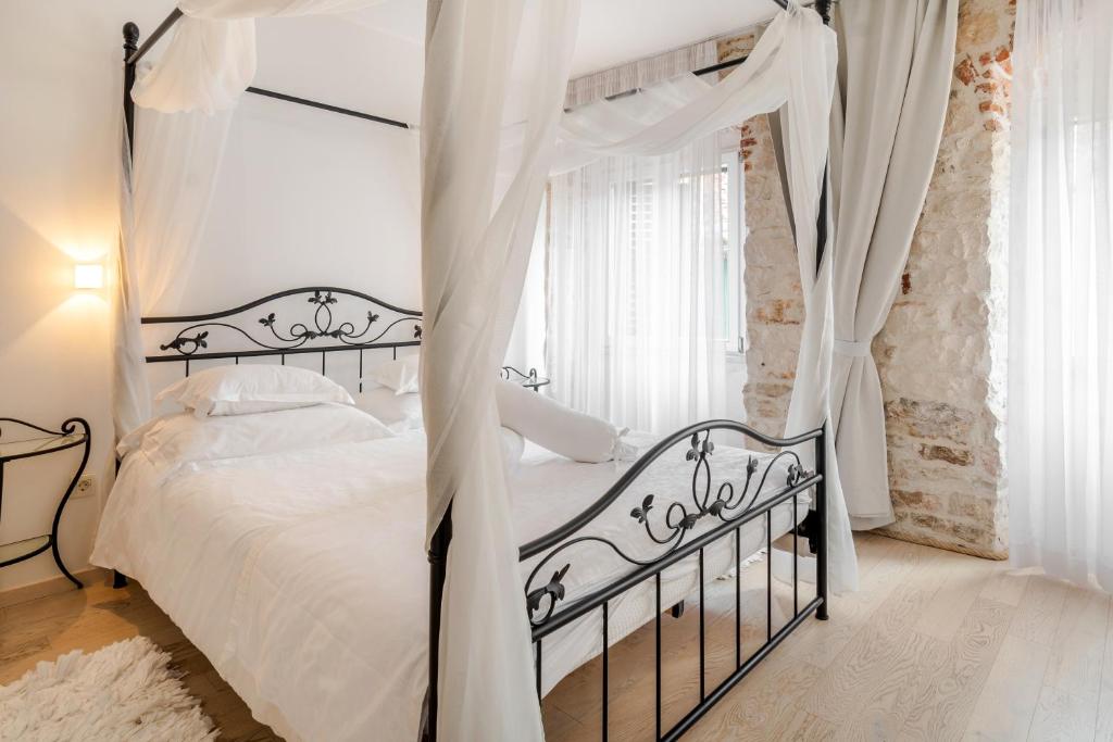 1 dormitorio con cama con dosel y cortinas blancas en Palace Tartaglia, en Split