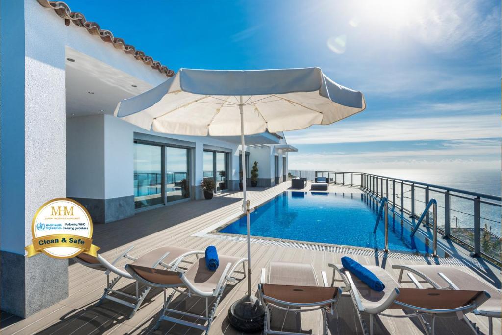 a pool with chairs and an umbrella on a balcony at Villa São Lourenço in Fajã da Ovelha