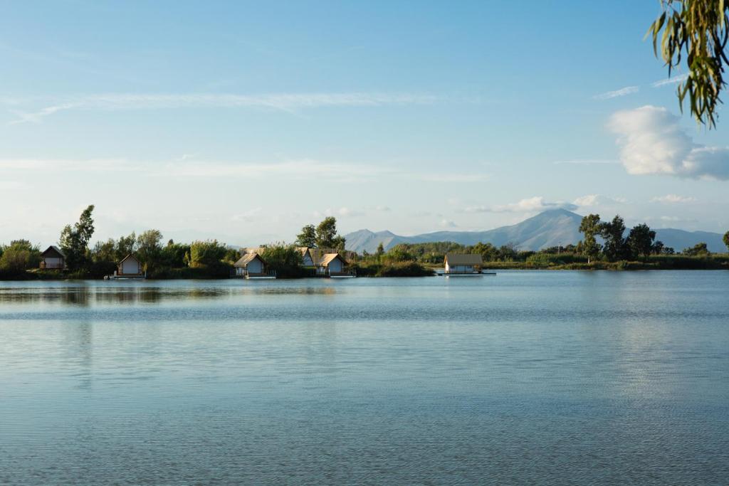 a large lake with houses and mountains in the background at Nabi Resort Glamping & SPA in Castel Volturno