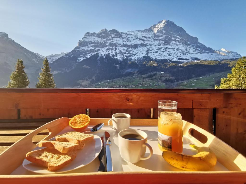 a tray with a plate of bread and coffee and a mountain at Chalet M in Grindelwald
