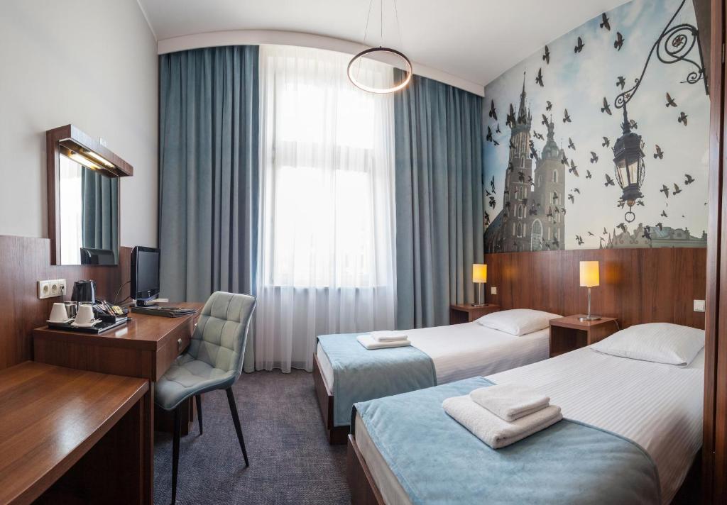 a hotel room with two beds and a desk at Hotel Downtown Kraków in Krakow