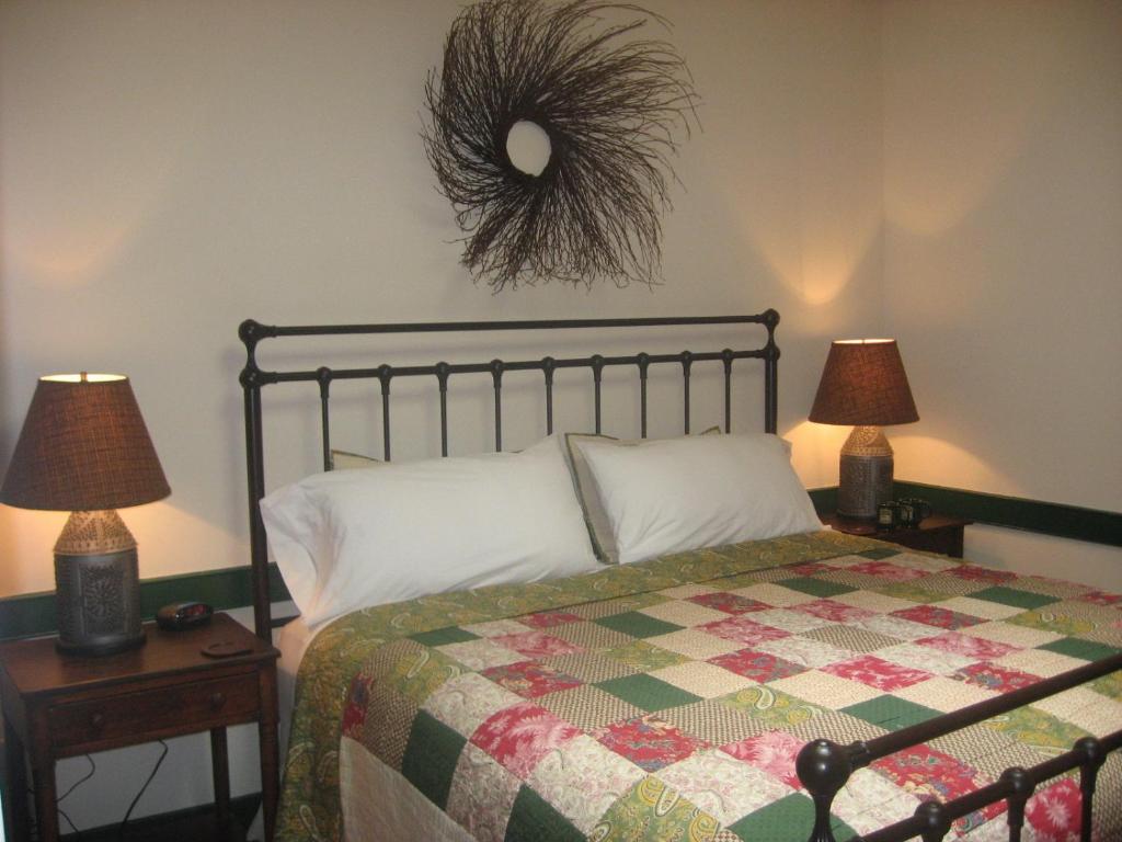 1 Schlafzimmer mit einem Bett mit einer Decke und 2 Lampen in der Unterkunft The Brafferton Inn in Gettysburg
