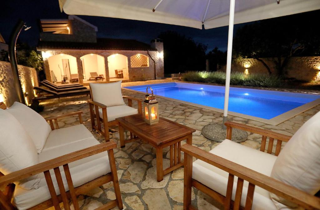 eine Terrasse mit Stühlen und ein Pool in der Nacht in der Unterkunft Vila SanAdrija in Drvenik Mali