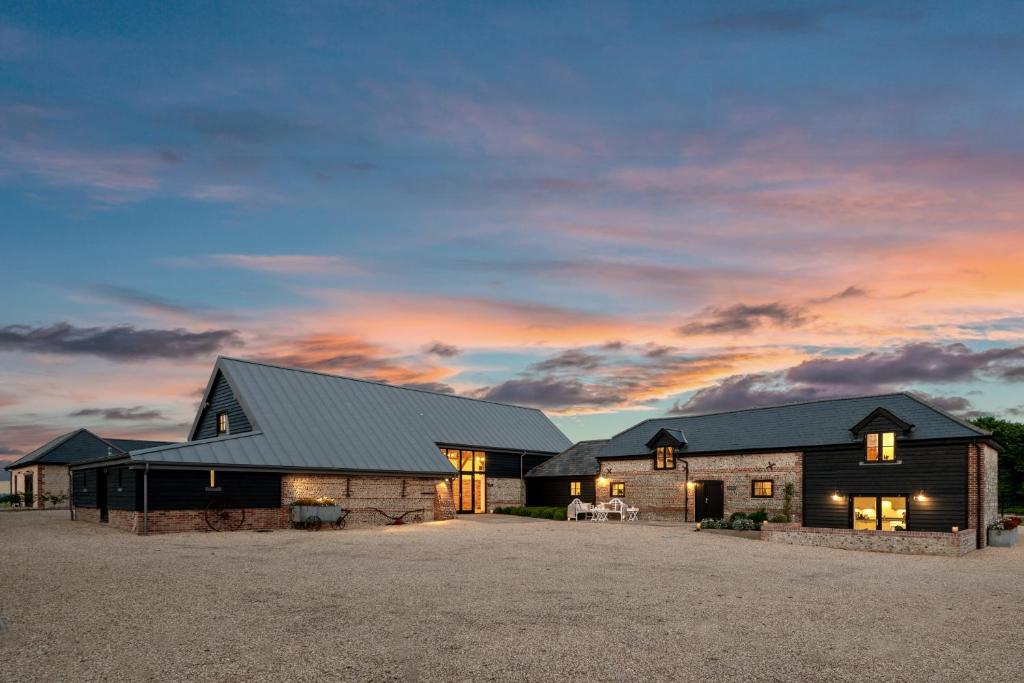 a barn style house with a sunset in the background at Barrow Hill Barns in Petersfield