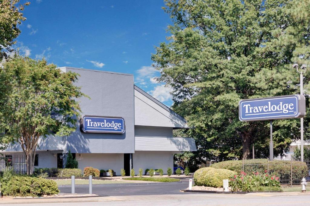 a building with two blue signs on the side of it at Travelodge by Wyndham College Park in Atlanta