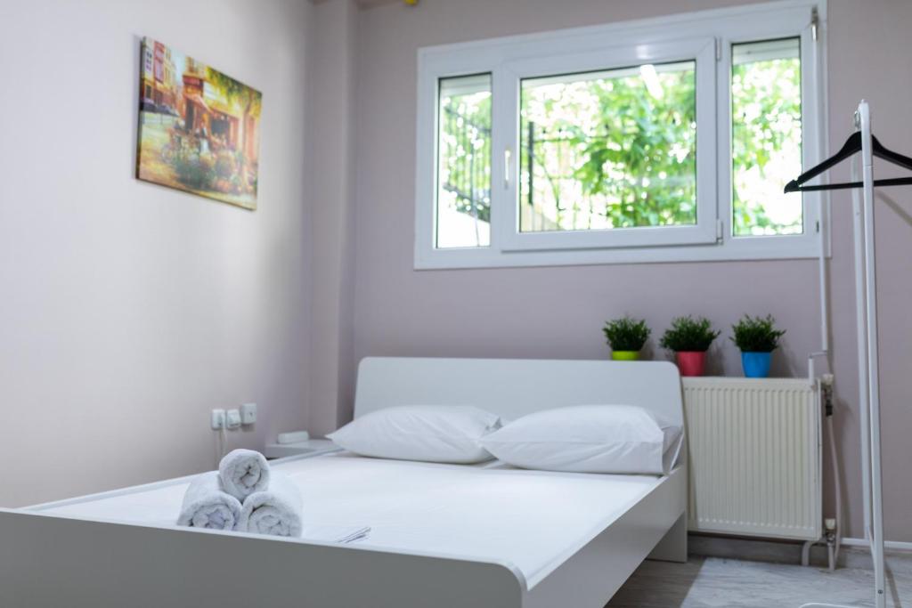 a white bed in a white room with a window at Xsoma Flats "Studio" in Thessaloniki