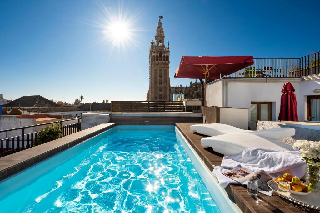 una piscina sul tetto di un edificio con torre dell'orologio di Cathedral Luxury Studio, Swimming Pool and Cathedral Views a Siviglia