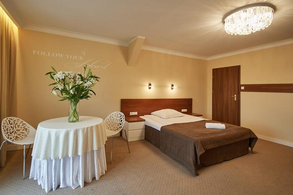 Hotel Melodia *** في Buk: غرفة نوم بسرير وطاولة مع إناء من الزهور