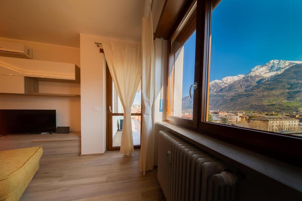 1 dormitorio con ventana grande con vistas a la montaña en Blue Moon - Via Parigi Apartments, en Aosta