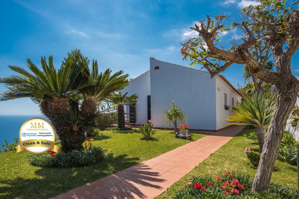 ein Haus am Strand mit Palmen und einem Schild in der Unterkunft Vivenda da Esquina - by LovelyStay in Caniço