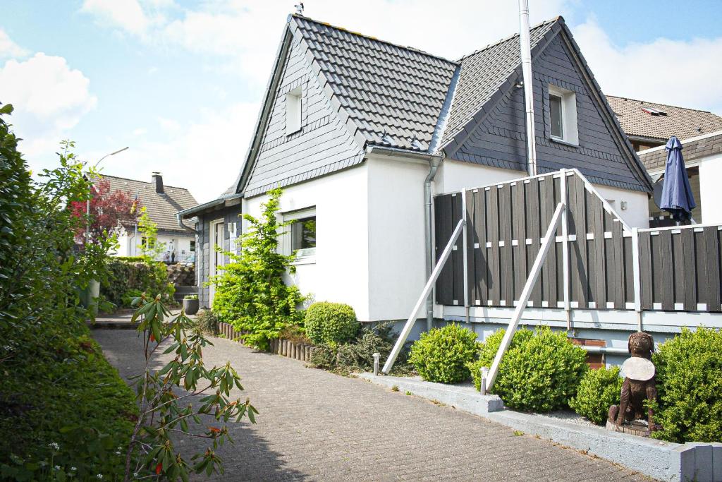 ein weißes Haus mit schwarzem Dach und einem Zaun in der Unterkunft Bergkrönchen Winterberg - Sauna - 8Beds - outdoor in Winterberg