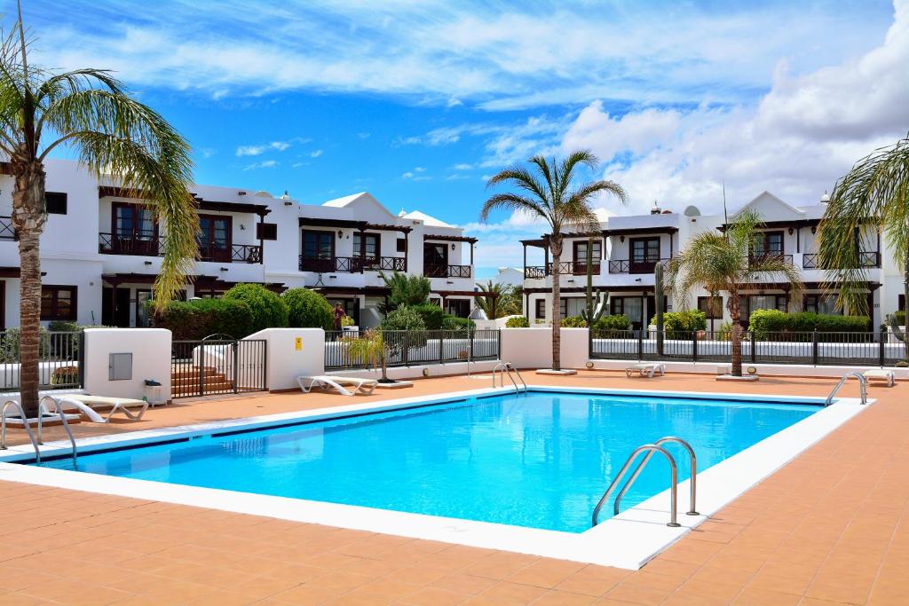 una piscina con palmeras frente a los apartamentos en Villa Papagyo, en Playa Blanca